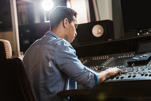 concentrated mixed race sound producer working at mixing console