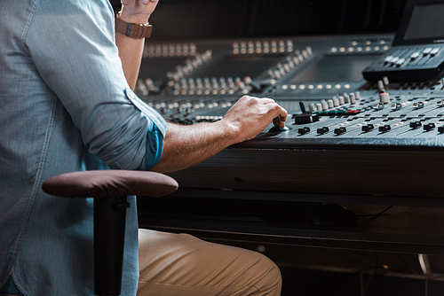 cropped view of mixed race sound producer working at mixing console