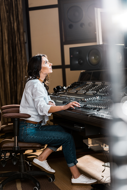 selective focus of attractive sound producer working at mixing console in recording studio