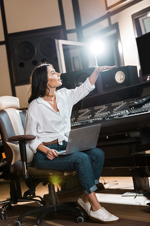 attractive sound producer gesturing while working in recording studio