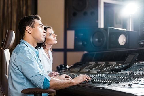 two multicultural musicians working at mixing console in recording studio