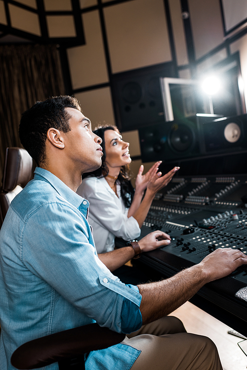 selective focus of sound producers working at mixing console in recording studio
