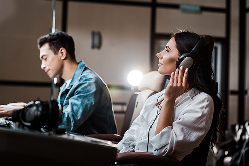 handsome sound producer working at mixing console while his colleague listening music in headphones