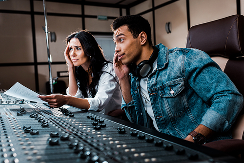 two thoughtful sound producers working at mixing console in recording studio