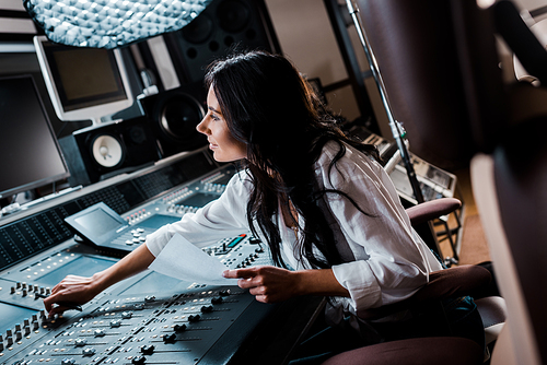 smiling sound producer working in recording studio at mixing console