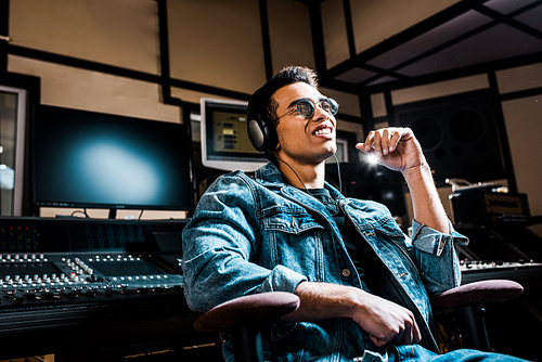 good-looking, mixed race sound producer in headphones listening music in recording studio