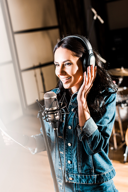 selective focus of inspired woman in headphones singing in recording studio