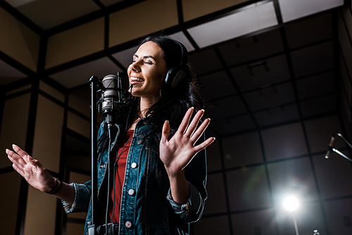 attractive inspired woman singing near microphone in recording studio