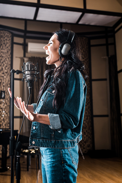 attractive emotional woman singing near microphone in recording studio