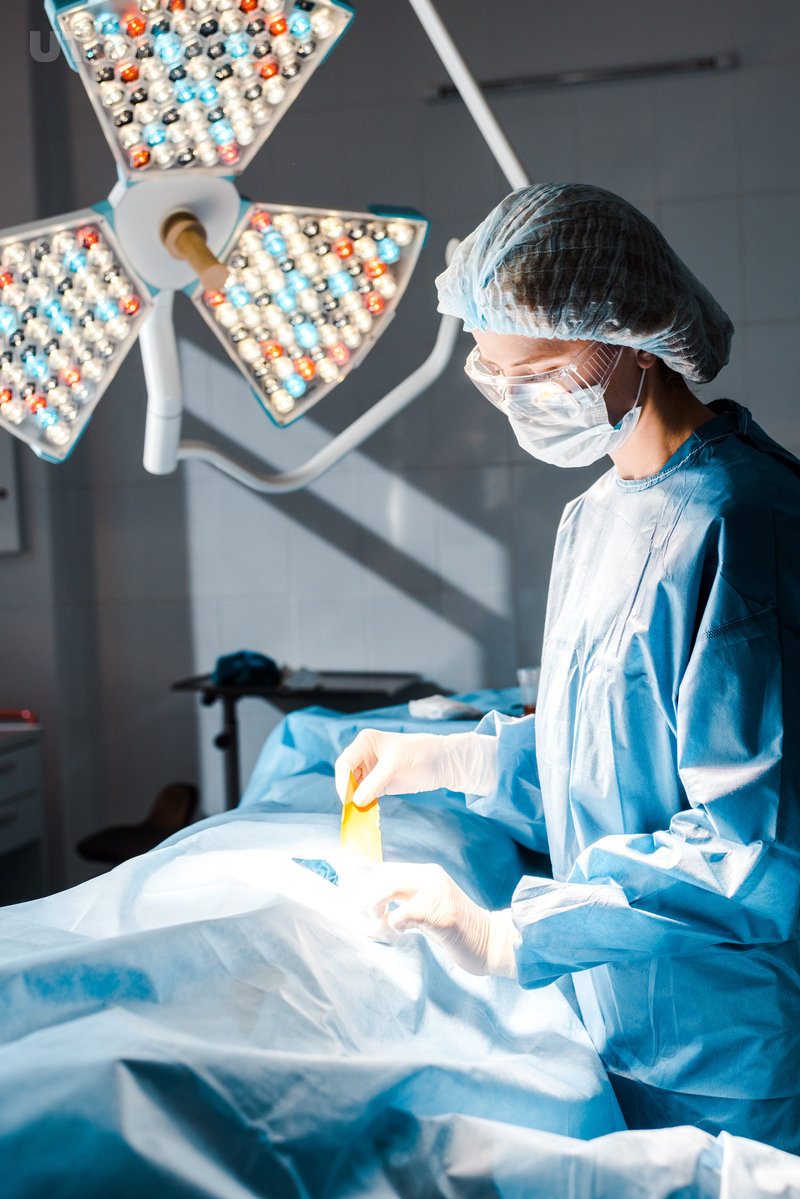 유토이미지 | nurse in uniform and medical cap holding strip in operating room
