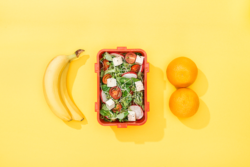 top view of  lunch box with salad near bananas and oranges
