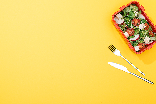 top view of lunch box with salad near fork and knife