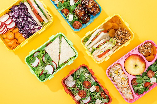 top view of lunch boxes with food on yellow background