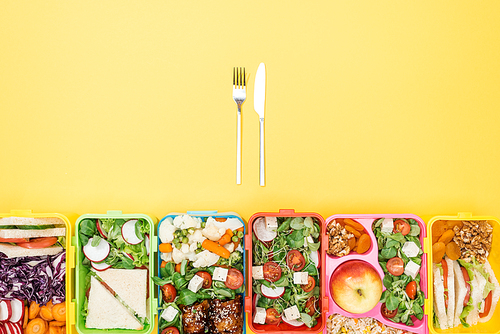 top view of fork and knife near lunch boxes with food