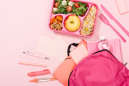 top view of lunch box with food near backpack and stationery