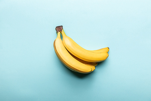 top view of ripe yellow bananas on blue background