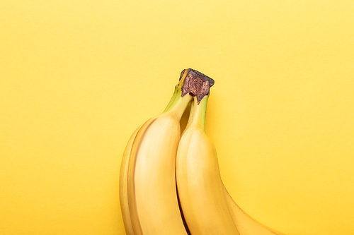 top view of ripe bananas on yellow background