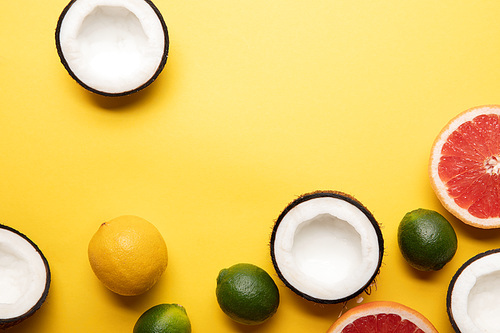 top view of citrus fruits and coconuts on yellow background with copy space