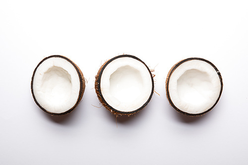 top view of ripe coconut halves on white background with copy space