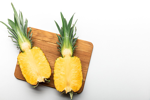 top view of cut ripe yellow pineapple on wooden chopping board on white background with copy space