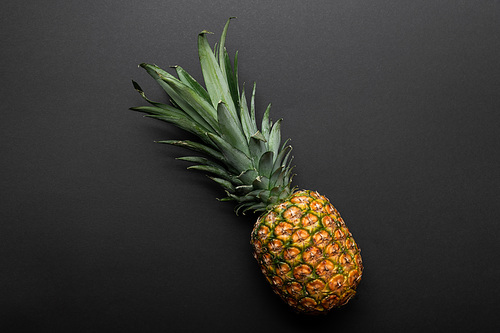 top view of ripe yellow pineapple on black background