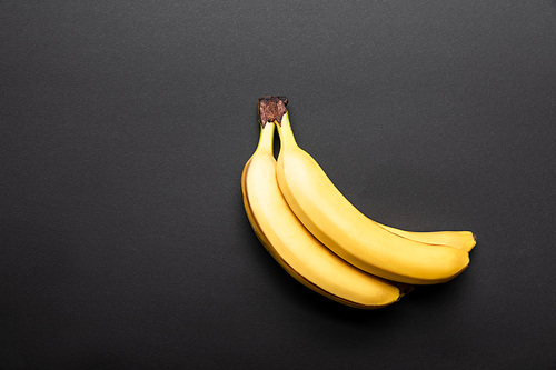 top view of ripe yellow bananas on black background with copy space