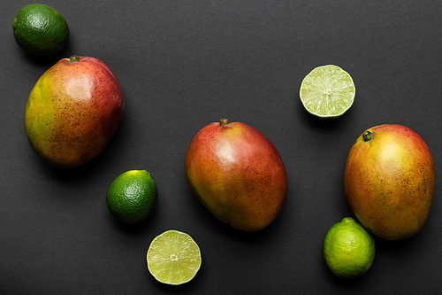 top view of ripe limes and mango on black background