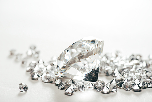 selective focus of sparkling pure big diamond among small on white background