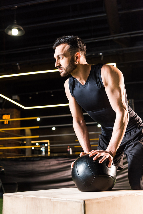 low angle view of serious man standing near box while holding ball