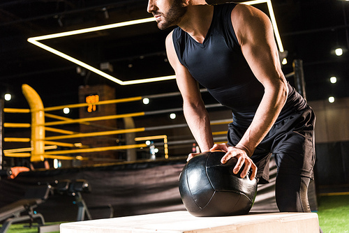 cropped view of serious man holding ball while standing near  box