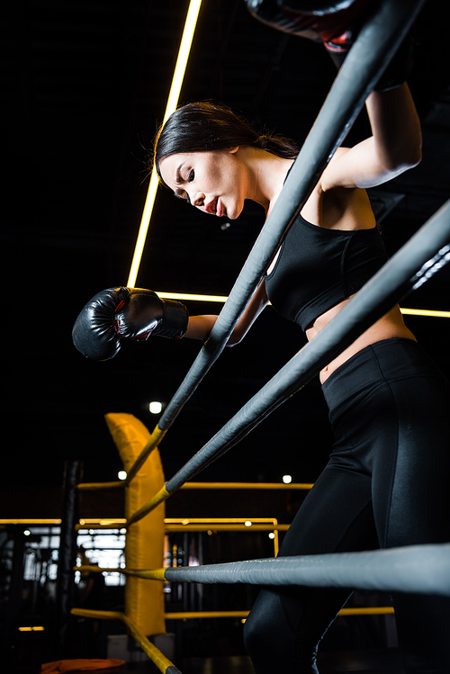low angle view of athletic woman in boxing gloves standing in gym