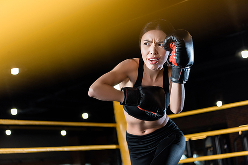 low angle view of young and confident woman boxing in boxing gloves