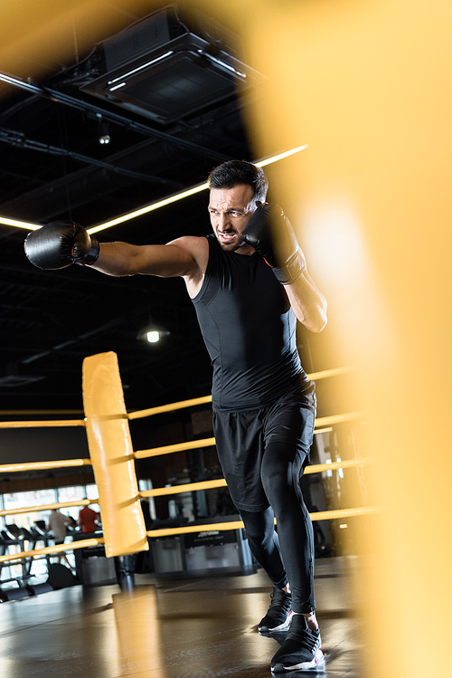 selective focus of strong bearded man boxing in sports center