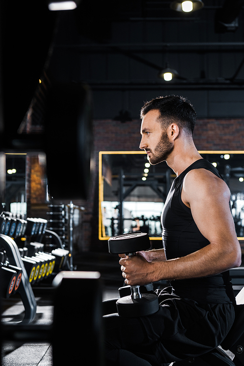 handsome athletic man working out with dumbbells in gym