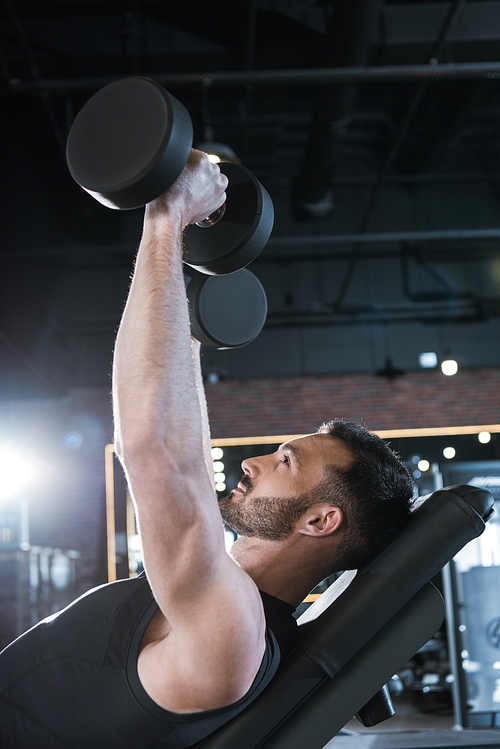 low angle view of happy man working out with dumbbells in gym