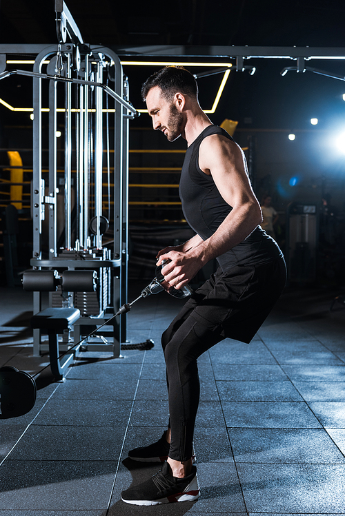 handsome athletic man exercising on training apparatus in gym