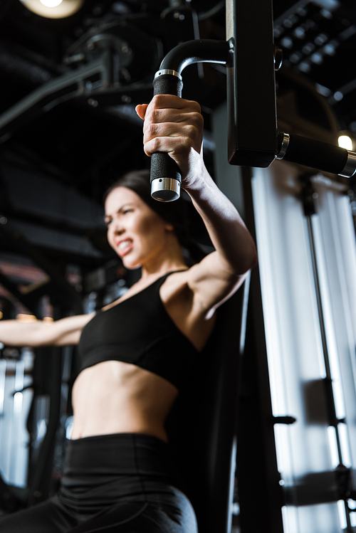 selective focus of sportswoman exercising on training apparatus in gym