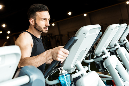 selective focus of handsome bearded man working out on exercise bike