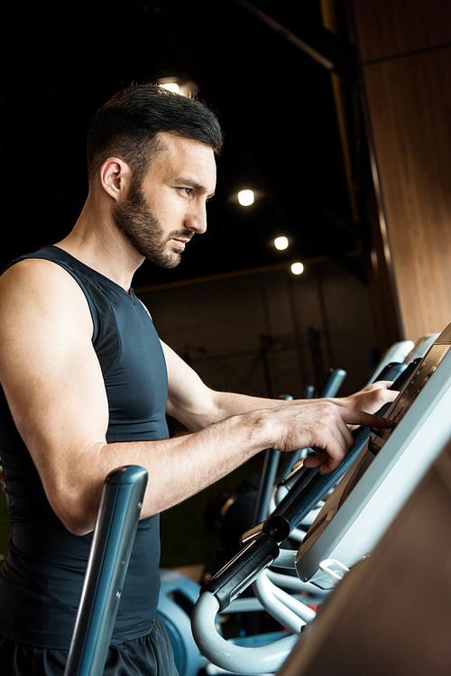 selective focus of handsome athletic man pointing with finger while standing near exercise bikes