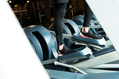 cropped view of athletic man working out on exercise bike in gym