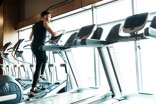 low angle view of athletic and handsome man working on out on exercise bike in gym