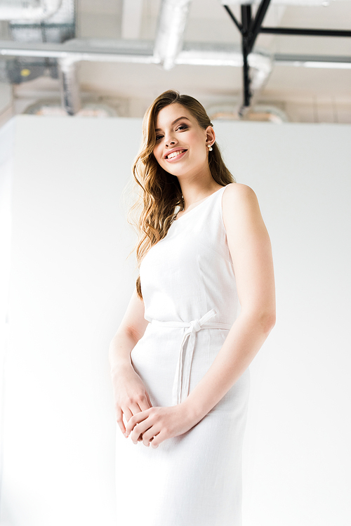 low angle view of smiling young woman in dress on white