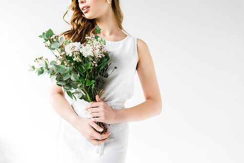 cropped view of young woman in dress holding flowers on white