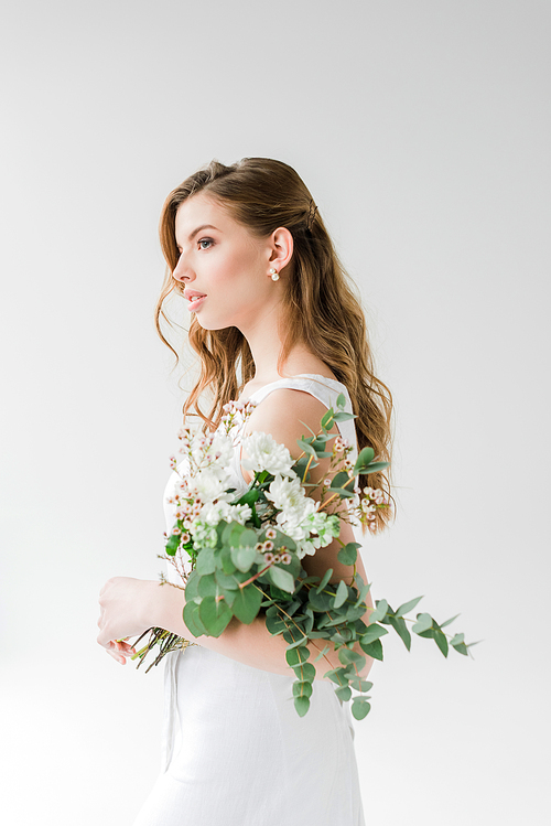 dreamy young woman in dress holding flowers on white