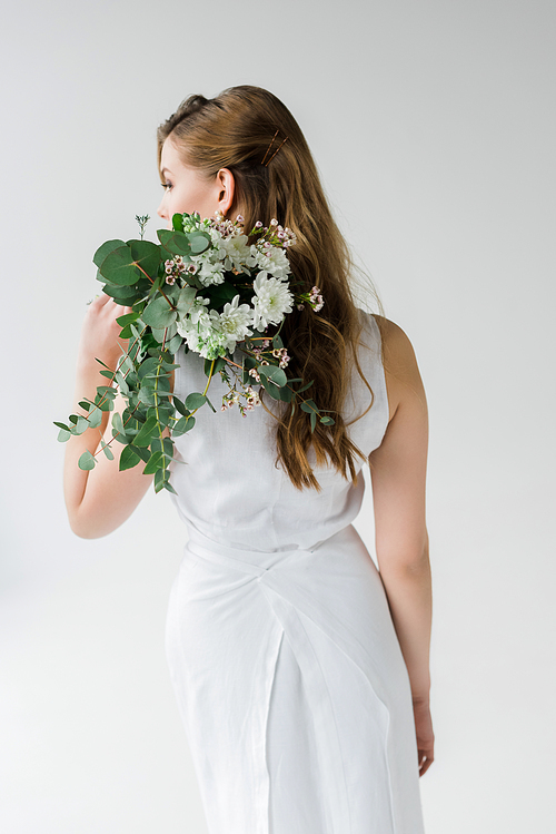 back view of girl in dress holding flowers behind back isolated on white