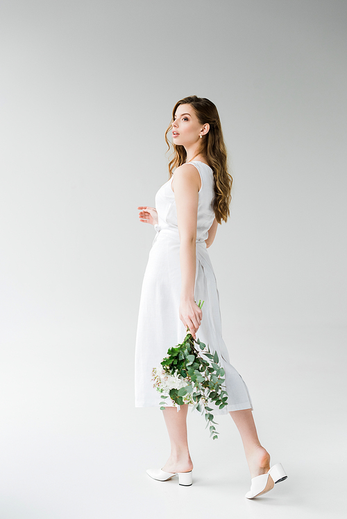 attractive girl in dress walking with flowers on grey