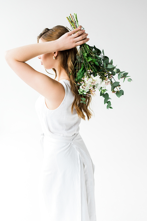 young woman in dress holding flowers behind back isolated on white