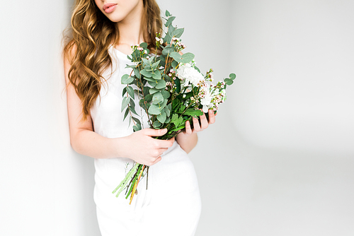 cropped view of girl holding bouquet of flowers on white