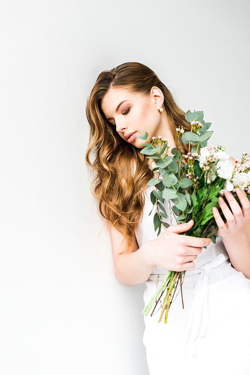 attractive young woman holding bouquet of flowers on white