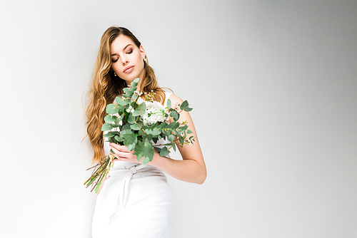 elegant girl in dress holding bouquet of chamelaucium and chrysanthemum flowers with eucalyptus leaves on white